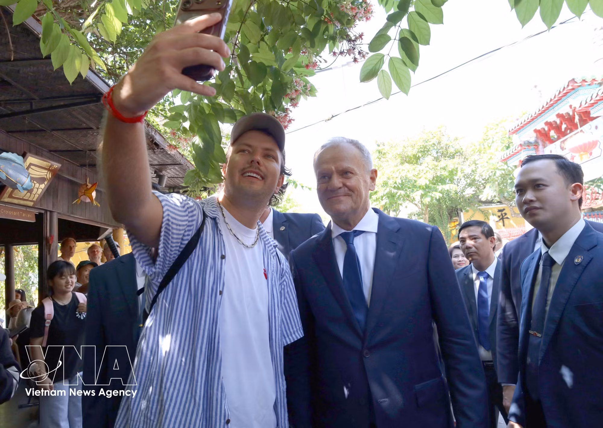 A tourist takes commemorative photos with Polish Prime Minister Donald Tusk in Hoi An Ancient Town. (Photo: VNA)