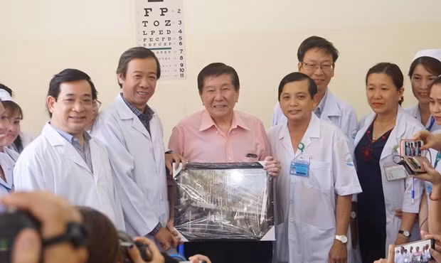 The 73-year-old patient (pink shirt) and medical workers pose for a photo when he is discharged from hospital on February 21 afternoon (Photo: VNA)
