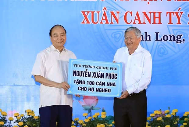 Prime Minister Nguyen Xuan Phuc (L) presents 100 houses for poor households (Photo: VNA)