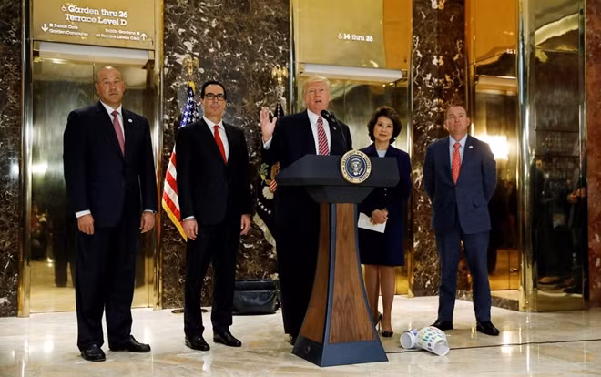 U.S. President Donald Trump is flanked by (L-R) Director of the National Economic Council Gary Cohn, Treasury Secretary Steven Mnuchin, Secretary of Transportation Elaine Chao and Director of the Office of Management and Budget Mick Mulvaney as he speaks about the violence, injuries and deaths at the "Unite the Right" rally in Charlottesville while talking to the media in the lobby of Trump Tower in Manhattan, New York, U.S., August 15, 2017.