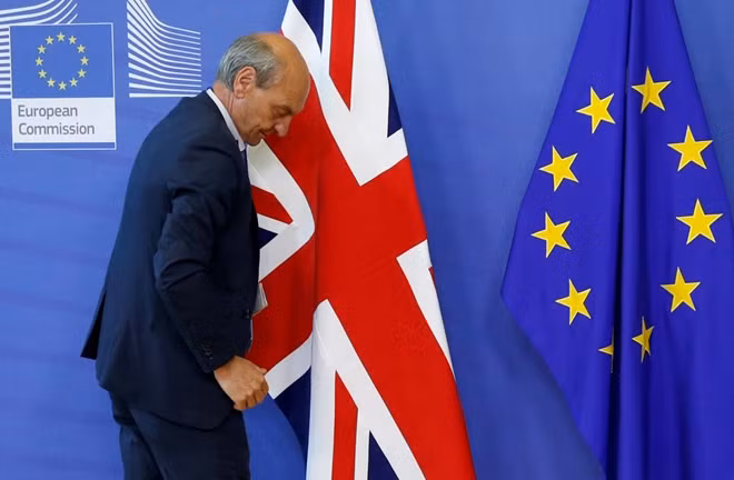 FILE PHOTO: A worker arranges flags at the EU headquarters as Britain and the EU launch Brexit talks in Brussels, June 19, 2017.