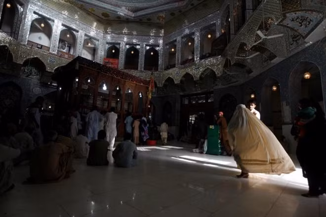 FILE PHOTO: A woman clad in burqa walks in the hallway of the tomb of Sufi saint Syed Usman Marwandi, also known as Lal Shahbaz Qalandar, in Sehwan Sharif, in Pakistan's southern Sindh province, September 5, 2013. REUTERS/Akhtar Soomro/File Photo.