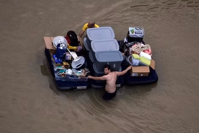 Residents wade with their belongings through flood waters brought by Tropical Storm Harvey in Northwest Houston. Photo: NYTimes