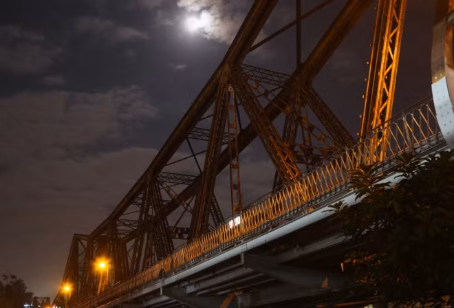The moon, said to be 30 percent brighter than usual, shines over the Long Bien Bridge in Hanoi.