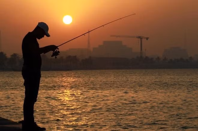 A man uses a rod to fish during sunset on the corniche in Doha, Qatar, June 15, 2017. REUTERS/Naseem Zeitoon