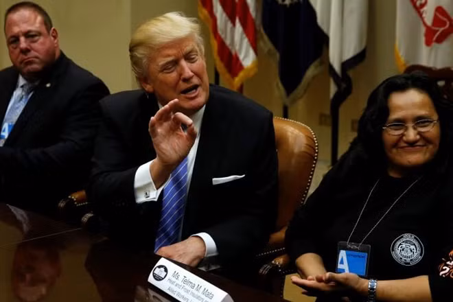 U.S. President Donald Trump (C), flanked by Gary Masino (L) of the Sheet Metal Workers Union and Telma Mata (R) of the Heat and Frost Insulators Allied Workers Local 24, holds a roundtable meeting with labor leaders at the White House in Washington, U.S. January 23, 2017. REUTERS/Jonathan Ernst