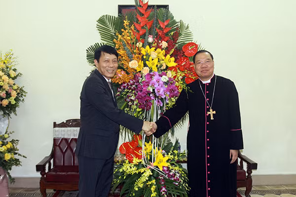 Deputy Minister Luong Tam Quang presents flowers to Archbishop Vu Van Thien and other dignitaries of the Hanoi Archdiocese.
