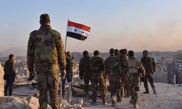 Syrian pro-government forces stand on top of a building in the Bustan al-Pasha neighbourhood of Aleppo. Photograph: George Ourfalian/Getty Images