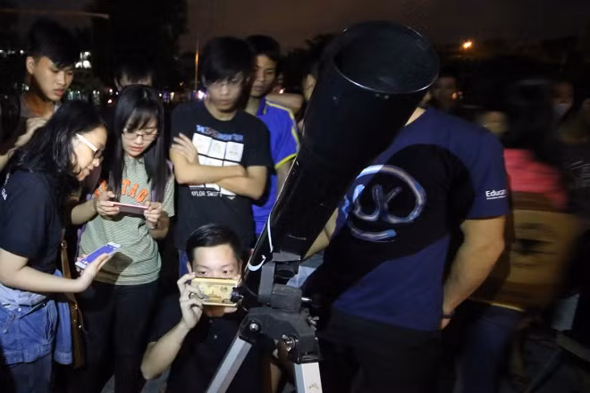 Young people watch the full moon at the sports center of Da Nang University of Technology.