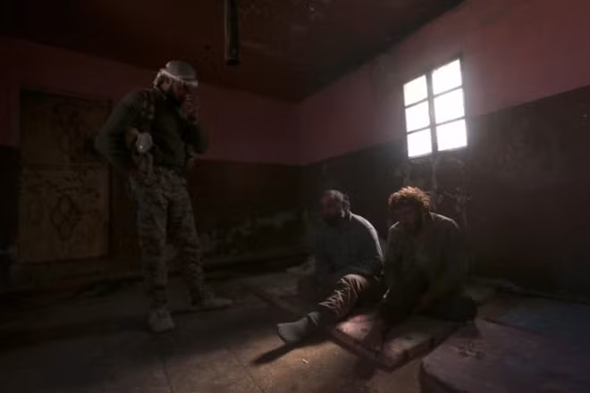 A Syrian Democratic Forces fighter stands near what he said was Islamic State fighters held prisioners by them, north of Raqqa city, Syria. REUTERS/Rodi Said