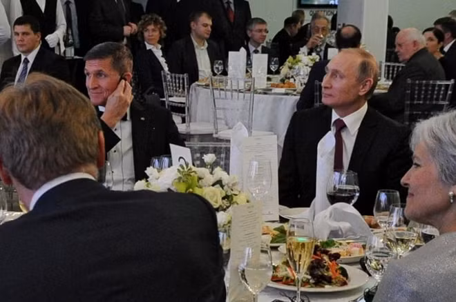 Russian President Vladimir Putin (R) sits next to retired U.S. Army Lieutenant General Michael Flynn (L) as they attend an exhibition marking the 10th anniversary of RT (Russia Today) television news channel in Moscow, Russia, December 10, 2015. Sputnik/Mikhail... REUTERS