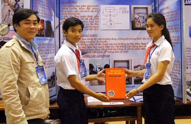 Tran Khanh Huy and Nguyen Thi Thu next to their fire alarm model