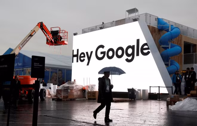 A man walks through light rain in front of the Hey Google booth under construction at the Las Vegas Convention Center in preparation for the 2018 CES in Las Vegas, Nevada, U.S. January 8, 2018. REUTERS/Steve Marcus/File Photo