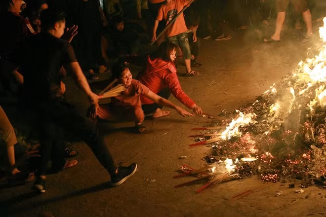 Hundreds of An Dinh villagers are trying to get fire from the pile of burning papers at the temple.