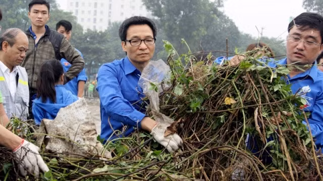 In the blue shirt of Vietnam’s Youth Volunteer movement, Deputy PM Vu Duc Dam (centre) joins students to clean Linh Dam Lake in response to World Kindness Day. Photo: dantri.com.vn