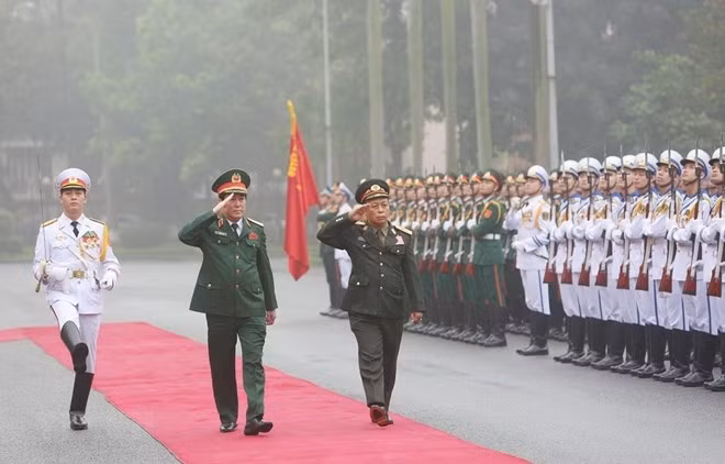 Chairman of the VPA’s General Department of Politics Gen. Luong Cuong (second, left) and Chairman of the LPA’s General Department of Politics Lt. Gen. Thongloi Silivong (third, left) review the guard of honour at the welcome ceremony in Hanoi on March 19 (Photo: VNA)