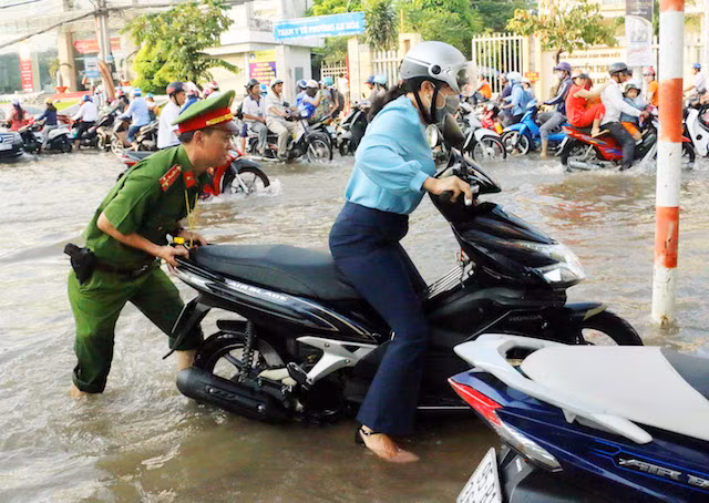 Police officer helps people through waterlogged areas.