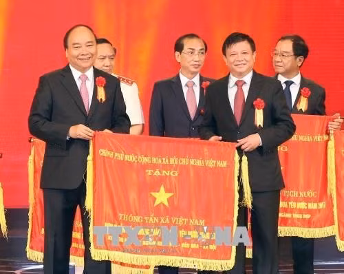 Prime Minister Nguyen Xuan Phuc (L) hands over the Government’s emulation flag to Vietnam News Agency (Source: VNA)