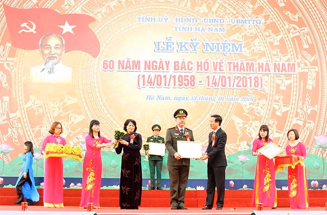 Mr. Thuong and Ms. Thinh presenting certificate of merit and flower to representative of the Ha Nam Provincial Police.