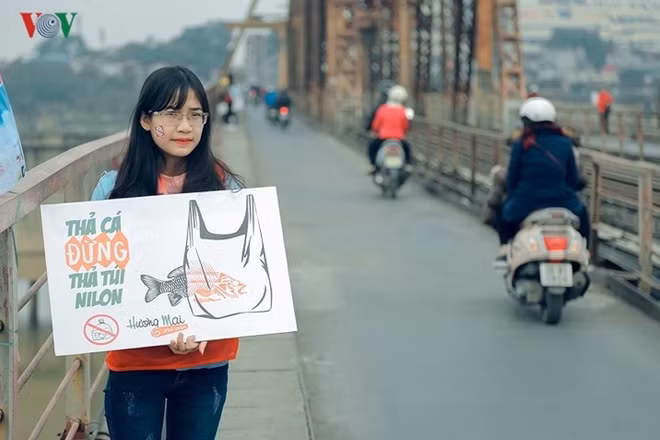 A volunteer holds a board to warn local people not to release fish in plastic bags to prevent environmental pollution.