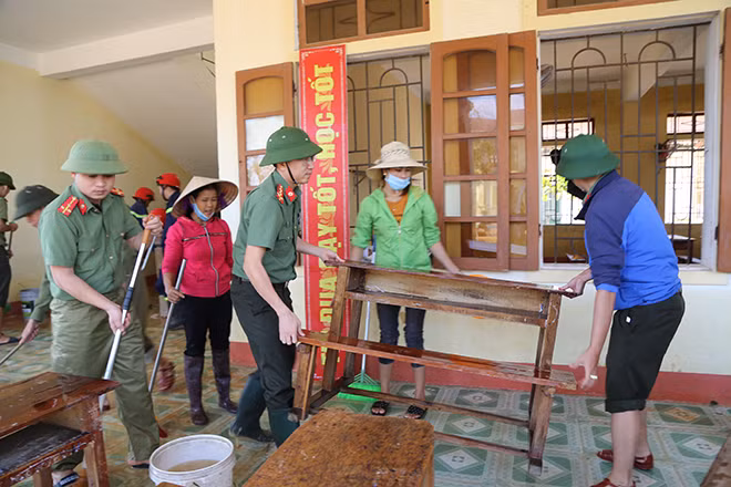 A police officer joins hand with a teacher to cleanup school facilities.