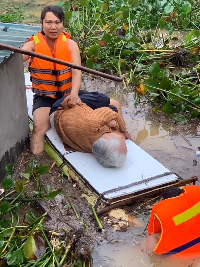 A policeman rows a raft to take bedridden 90-year-old woman to a safer place.