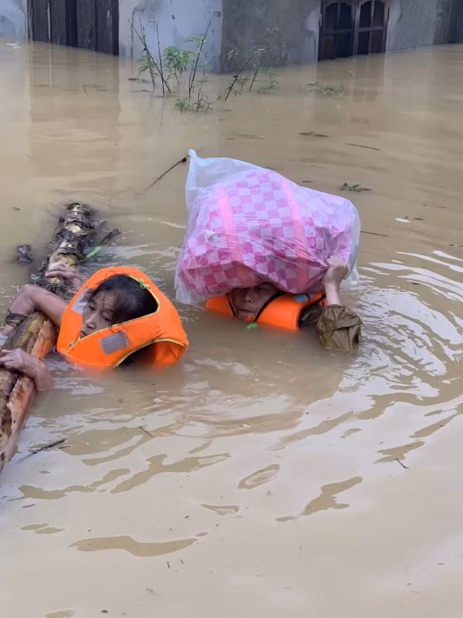 Police soldiers carry assets and pull banana stem rafts with people on it out of flooded area.