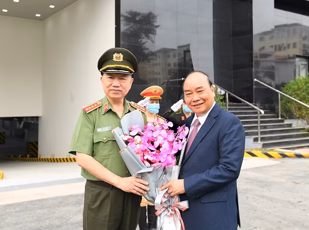 Minister To Lam presents flowers to Prime Minister Nguyen Xuan Phuc.
