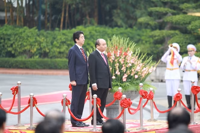Prime Minister Nguyen Xuan Phuc and Prime Minister Shinzo Abe saluting the flags