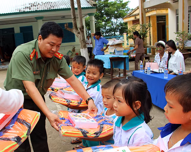 Needy students receiving gifts from a representative of the Public Security Newspaper.