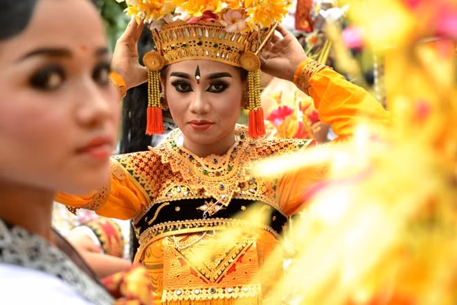 A Balinese girl adjusts her headdress before taking part in a traditional dance during in a cultural parade at a festival to mark the New Year in Denpasar