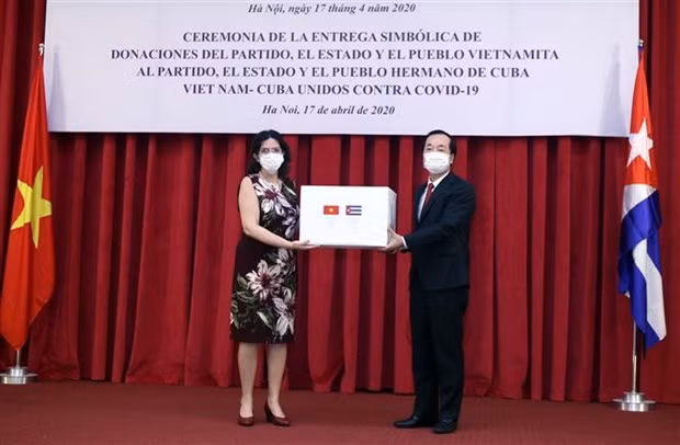 Minister of Construction Pham Hong Ha (R) presents the token of the relief package to Cuban Ambassador Lianys Torres Rivera (Photo: VNA)