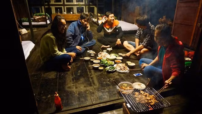 Tourists enjoy a barbecue dinner at the house, with some ingredients picked from the front yard.