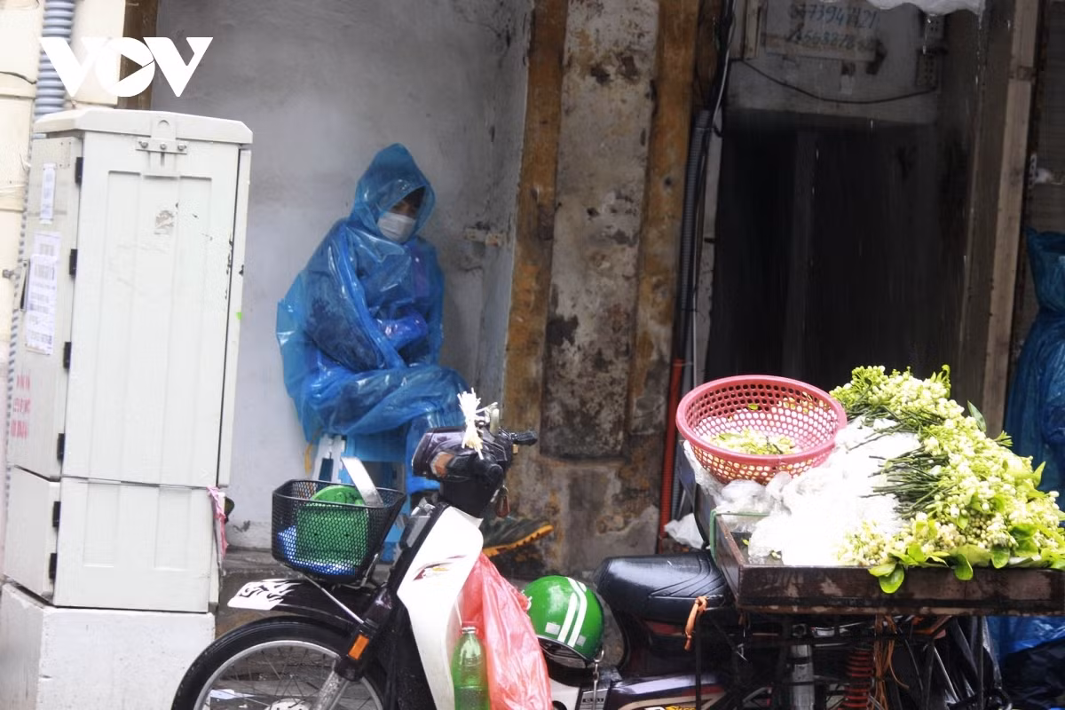 A street vendor seeks shelter to avoid drizzle.
