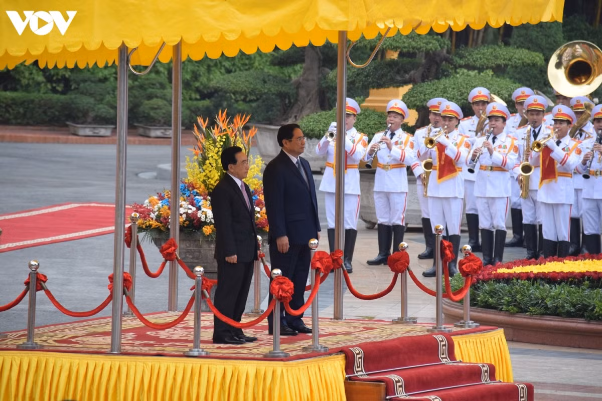 Prime Minister Pham Minh Chinh invites Lao Prime Minister Phankham Viphavanh to the podium, while the military band plays the national anthems of the two countries.