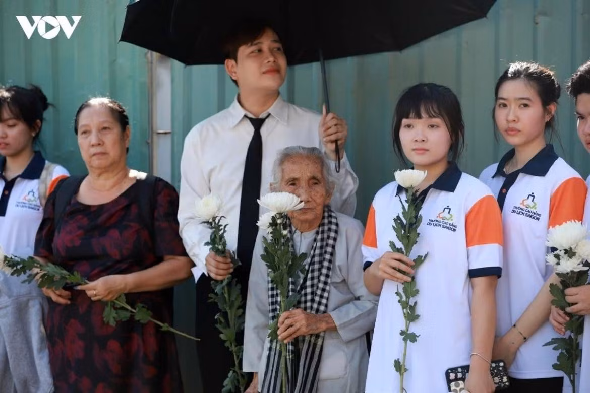 Local residents, holding white chrysanthemums, line the route to pay their respects to the 731 sets of martyrs’ remains as the convoy passes by.