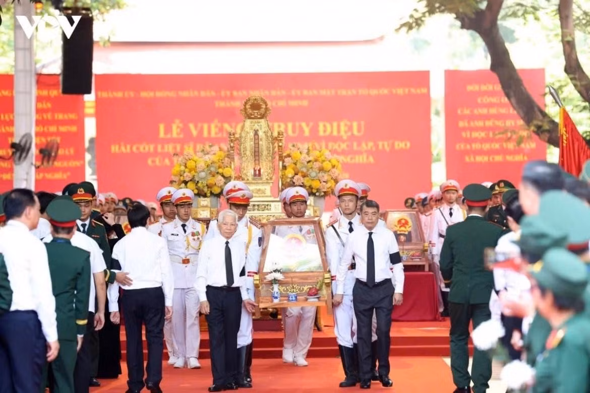 Prime Minister Le Minh Hung and former State President Nguyen Minh Triet stand on either side of the coffin of a fallen soldier during the memorial service.