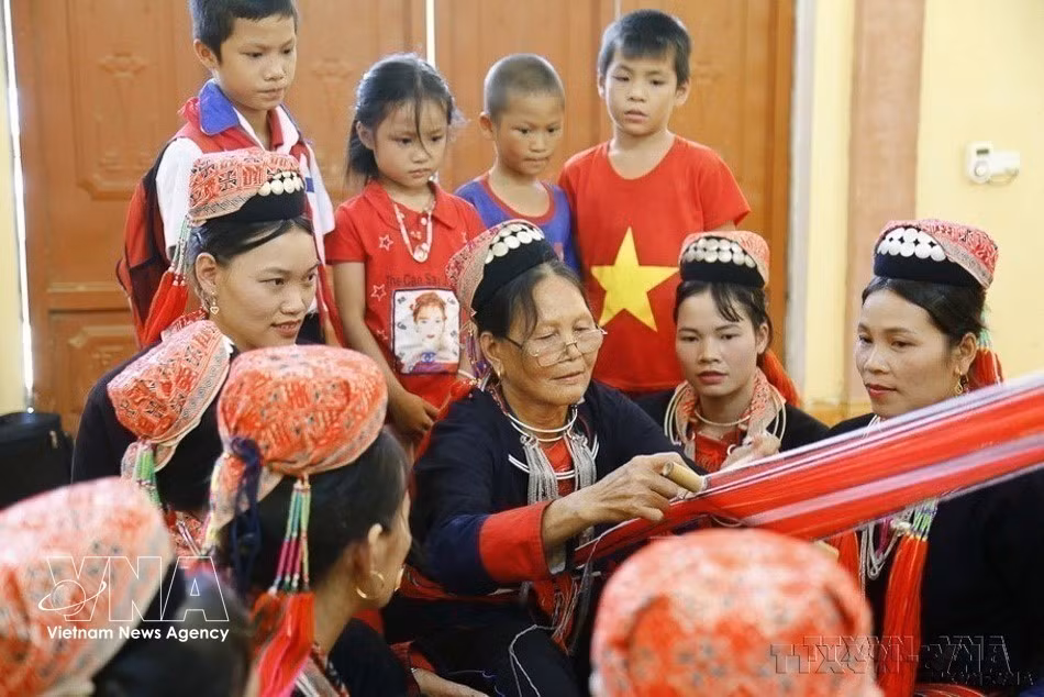 An elderly woman from the Dao Thanh Y Club in Eo village in Tuyen Quang province passes down the traditional brocade weaving craft of the Dao ethnic group to young people (Photo: VNA)