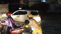 Traffic police support people in passing waterlogged road sections during night