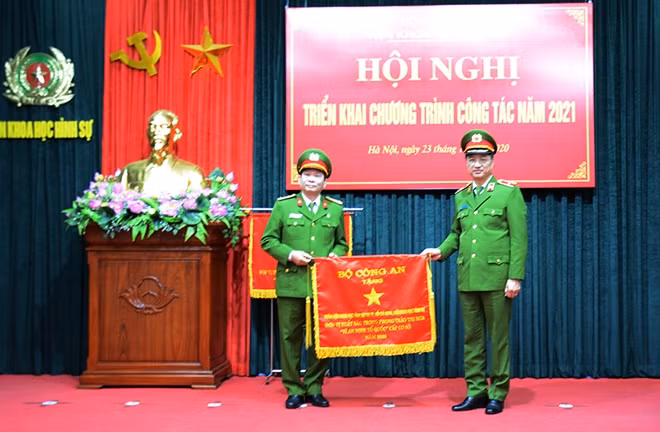 On behalf of the Ministry of Public Security, Deputy Minister Nguyen Duy Ngoc presenting the Emulation Flag to the Ho Chi Minh City-based branch of the Institute of Criminal Sciences.