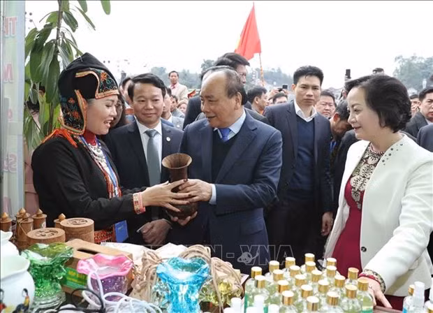 Prime Minister Nguyen Xuan Phuc takes a look at traditional products made by people in Tran Yen district, Yen Bai province on his visit here. (Photo: VNA)