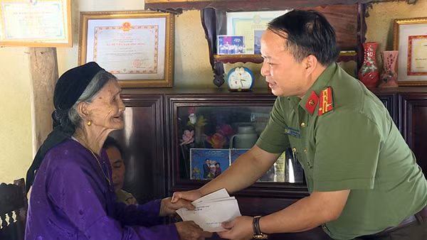 Senior Colonel Phan Huy Ngoc present gift to Vietnamese Heroic Mother Hoang Thi Van.