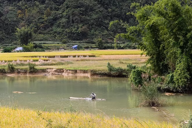 A man pulls a fishing net in a stream down the waterfall.