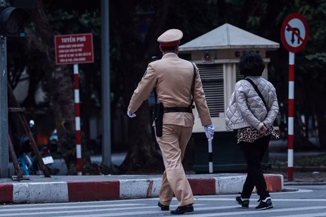 A traffic police officer is helping a woman crossing the road.