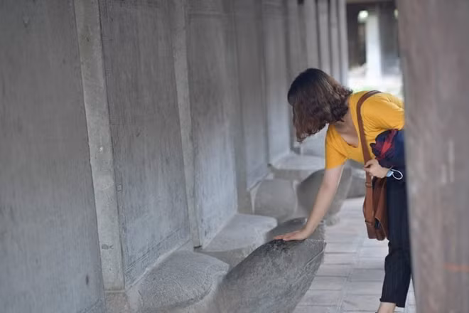 Some students rubs stone turtles' heads. These turtle statues carry the names of doctorate students from 1442 to 1779 on them, and many believe this practice brings them good luck.