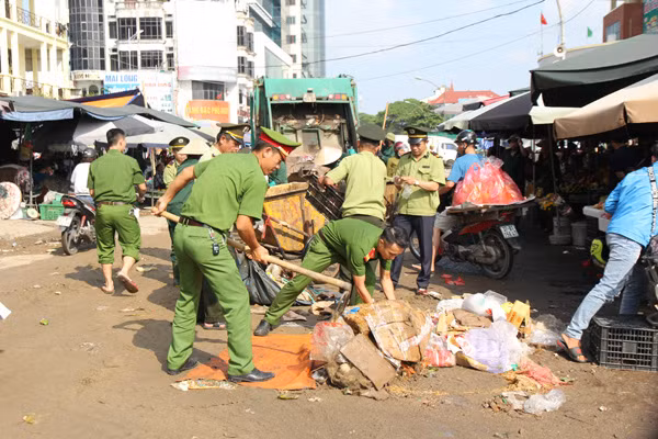 Hong Son Ward police and environmental sanitation workers in Vinh city clear wastes in front of Vinh market.