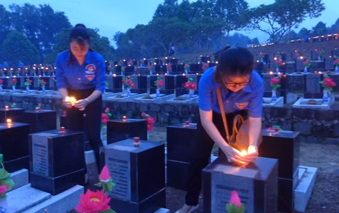 Young people light candles on graves of fallen soldiers at the provincial martyrs' cemetery in the southern province of Binh Phuoc on July 26. (Photo: VNA)