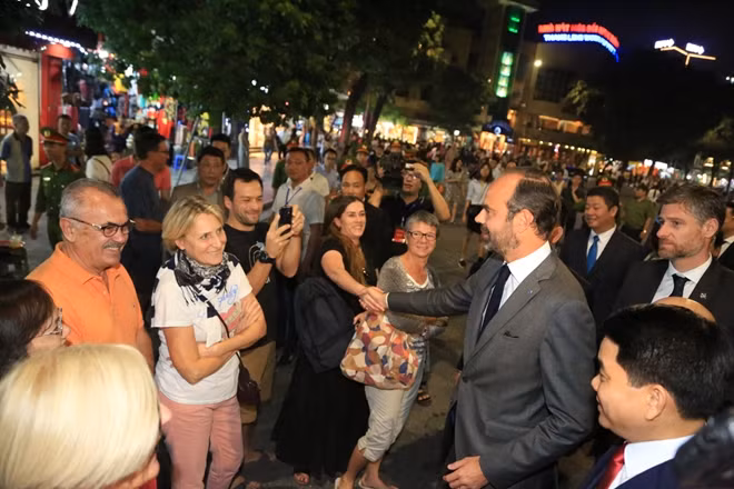 The French Prime Minister happily shakes hands with French tourists in Hanoi.