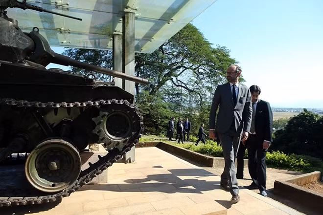 The French PM stands next to a French tank destroyed on Hill A1 during the Dien Bien Phu campaign.