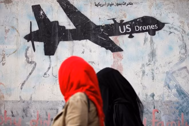 Women walk past a graffiti, denouncing strikes by U.S. drones in Yemen, painted on a wall in Sanaa, Yemen February 6, 2017. REUTERS/Khaled Abdullah 1/2leftright 2/2leftright 1/2